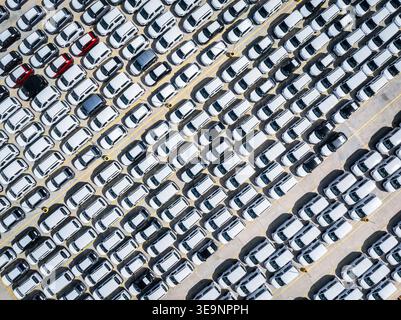 Vue aérienne de haut en bas des rangées de voitures neuves prêtes à l'exportation dans un port terminal commercial Banque D'Images