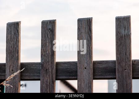 Planches de clôture en bois altérées contre le ciel lumineux de près. Fond extérieur rustique avec espace de copie et composition minimale. Banque D'Images