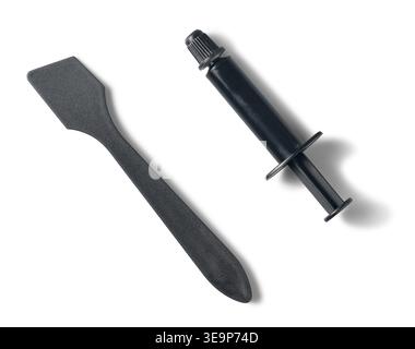 seringue de pâte thermique noire avec spatule d'épandeur en plastique fond blanc isolé, outil de refroidissement de matériel informatique, vue de dessus, modèle de maquette Banque D'Images