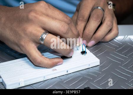Un homme travaille sur un circuit imprimé avec une montre au poignet. Il est concentré sur la tâche à accomplir et il s'amuse Banque D'Images