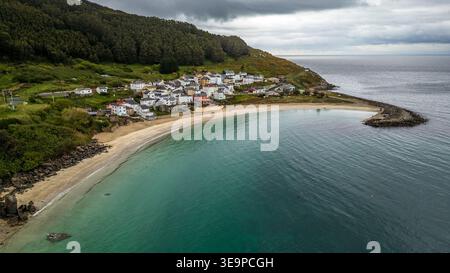 Superbe vue aérienne de Porto de Bares. La photo met en valeur la plage en croissant aux eaux turquoises, le petit village balnéaire aux maisons blanches, et Banque D'Images