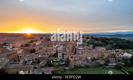 Un coucher de soleil doré enveloppe le village médiéval de Pals, en Catalogne. La vue aérienne montre les tons chauds du soleil sur les maisons en pierre, la Torre de le Banque D'Images