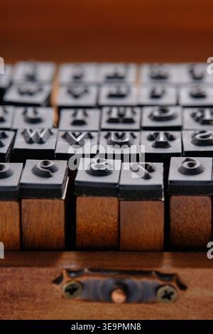 Gros plan vertical poinçonnage de lettres en caoutchouc sur des blocs de bois à l'intérieur d'un vieux couvercle de boîte de rangement Banque D'Images