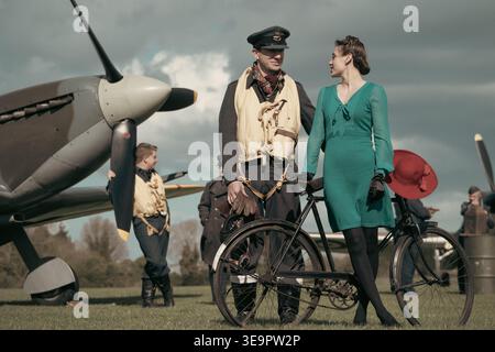 Pilote de la RAF en gilet de sauvetage discute avec une femme en robe verte à côté de Spitfire MkVc EE602 lors de la reconstitution de Sywell Battle of Britain Banque D'Images