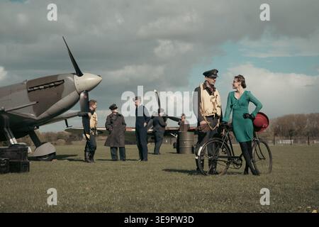 Le pilote de la RAF en casquette et gilet de sauvetage discute avec une femme en robe verte à côté de Spitfire MkVc EE602 à Sywell Aerodrome reconstitument Banque D'Images