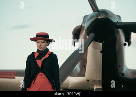 Une femme dans les années 1940 robe de guerre se tient seule devant le Spitfire MkVc EE602 à Sywell Aerodrome, Northamptonshire. Banque D'Images