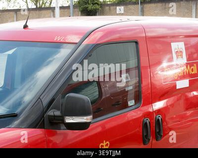Gros plan de la fenêtre côté conducteur d'une camionnette de livraison Royal mail dans une rue du Royaume-Uni, montrant une livrée rouge emblématique et un reflet d'un véhicule voisin dans la vitre Banque D'Images