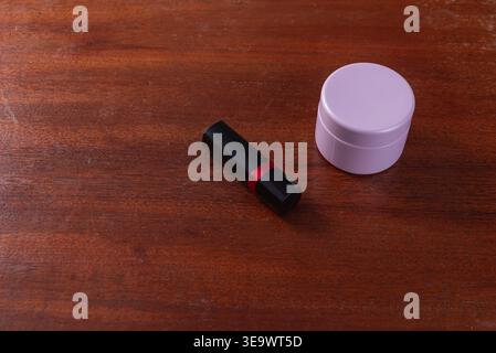 Nature morte avec rouge à lèvres avec bande rouge et crème cosmétique de lavande sur fond de bois. Lumière douce et diffuse. Configuration minimaliste pour la beauté, wellnes Banque D'Images