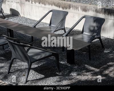 Mobilier d'extérieur moderne de style loft avec chaises en métal noir et table sur sol en gravier, avec design industriel minimaliste, patio contemporain, Banque D'Images