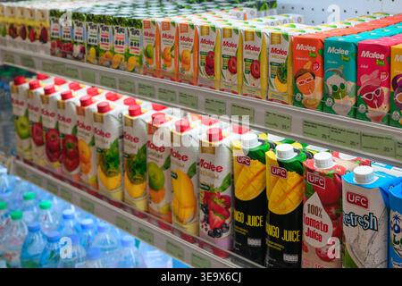 Un plan horizontal à grand angle montre plusieurs rangées de cartons de jus de fruits soigneusement organisés sur les étagères de supermarchés réfrigérés à Karon, Phuket. Promin Banque D'Images