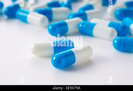 Gros plan de capsules bleues et blanches sur fond blanc, macro plan de pilules médicales avec une faible profondeur de champ Banque D'Images