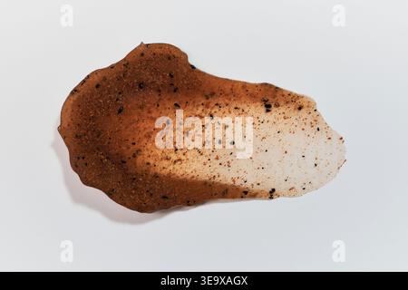 Échantillon de produit cosmétique exfoliant brun avec des granules sur fond blanc Banque D'Images
