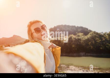 Femme Selfie Mountains paysage - femme souriante prend un selfie devant une chaîne de montagnes. Banque D'Images