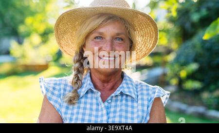 Heureuse femme âgée profitant d'une journée ensoleillée dans le jardin. Banque D'Images