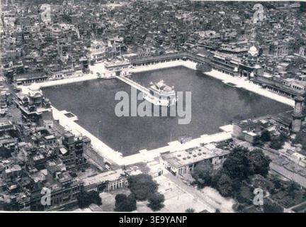 Le Temple d'Or (Harmandir Sahib), situé à Amritsar, au Pendjab, est le site le plus sacré du Sikhisme. Cette vue aérienne capture la grandeur du temple et de son complexe environnant, y compris le Sarovar (réservoir d'eau sacrée). L'image est une photographie d'archives du milieu du XXe siècle, mettant en valeur la beauté architecturale et l'importance culturelle du temple. Banque D'Images