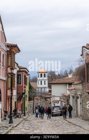 Les touristes explorent les anciennes rues pavées de Plovdiv, Bulgarie. Avec des maisons historiques colorées et une belle tour d'église orthodoxe sous Banque D'Images