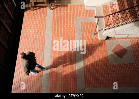 Homme marchant sur le chemin de brique avec de longues ombres de vue de dessus Banque D'Images