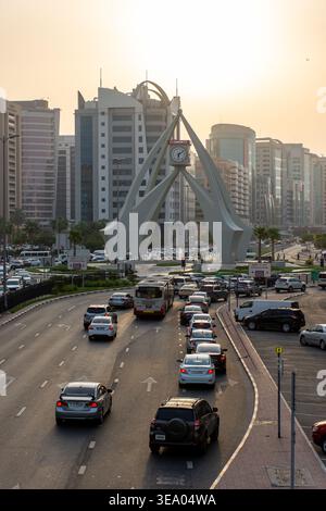 Vue surélevée de la circulation dense approchant le monument emblématique de la tour de l'horloge Deira au coucher du soleil à Dubaï, Émirats arabes Unis. Banque D'Images
