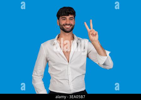 Homme joyeux souriant, montrant un signe de paix, représentant la victoire ou le succès Banque D'Images
