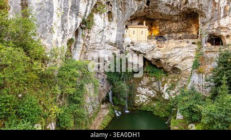 Vue aérienne du Santuario de Covadonga niché dans une grotte spectaculaire, avec une cascade qui tombe en cascade dans une piscine sereine ci-dessous, Santa Cueva de Covadonga, C. Banque D'Images
