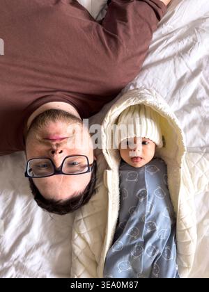 Père et nouveau-né reposant ensemble sur le lit Banque D'Images