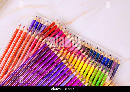 Les crayons de couleur sont placés ensemble dans un emballage transparent sur fond blanc sous lumière naturelle. Banque D'Images