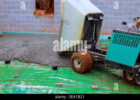 Le godet de brouette verse du béton sur le chantier de construction les ouvriers préparent le sol à l'aide d'outils Banque D'Images