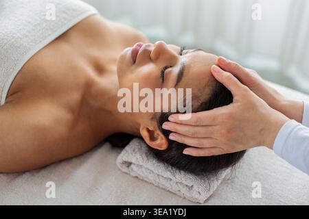 Gros plan d'une femme afro-américaine recevant un massage de la tête au spa Banque D'Images