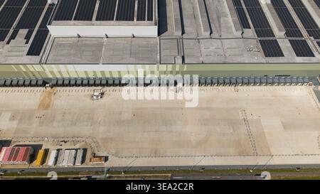 Vue aérienne d'un centre de distribution de supermarché avec de nombreuses baies de chargement, des panneaux solaires sur le toit et une grande cour de béton à Nailstone, Nun Banque D'Images