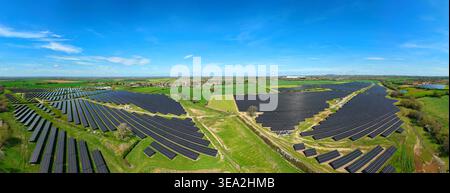 Vue aérienne d'une grande ferme solaire avec des rangées de panneaux photovoltaïques à travers des champs verts sous un ciel bleu clair à Nailstone, Angleterre, Royaume-Uni. Banque D'Images