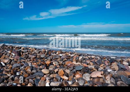 Côte de pierre de la mer du Nord faite de petits pavés. Pierres sur la plage. Galets sur le littoral. Banque D'Images