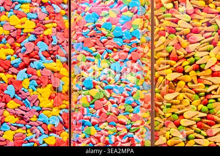 Divers bonbons gommeux colorés dans des distributeurs transparents. Bonbons gelés en forme de coeur et en forme de cône dans un magasin de bonbons. Fond de nourriture lumineux. Banque D'Images