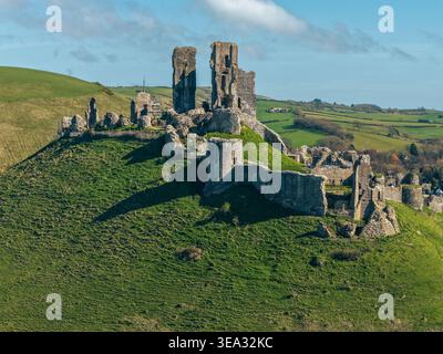 Vue aérienne par drone des ruines du château de Corfe sur sa colline à la lumière du soleil d'hiver, île de Purbeck, Dorset, Angleterre Banque D'Images