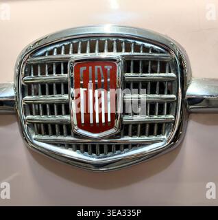 Vue rapprochée d'une calandre de radiateur de voiture Fiat 500 vintage des années 1960 avec un logo de marque rouge et chromé sur un capot ou un capot rose pâle Banque D'Images