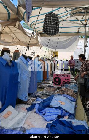Rome, Italie - 19 avril 2026 : un client regarde diverses chemises pour femmes et chemisiers légers exposés sur des mannequins et des tables. Une affiche rose « Stock » Banque D'Images
