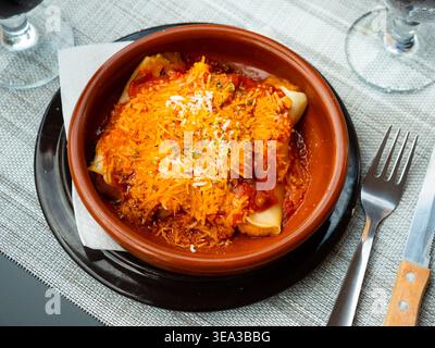 Délicieux cannelloni aux pâtes avec sauce à la viande et à la tomate servis dans une assiette en argile. Plats italiens traditionnels Banque D'Images