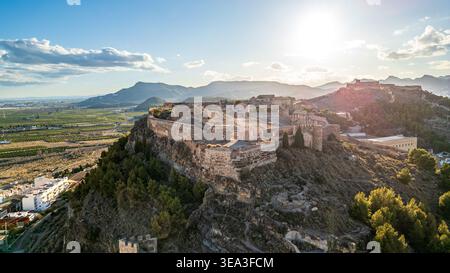 Une vue aérienne évocatrice du château de Sagunto baignée par la lumière du coucher de soleil. L'image met en évidence les vastes fortifications et bastions que domi Banque D'Images