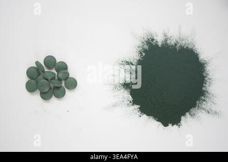 Spiruline comprimés et poudre sur une surface blanche Banque D'Images