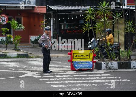 Bandung, Indonésie - 2 février 2026 - Un policier de la circulation en uniforme surveille un passage à niveau à Bandung, en Indonésie. La scène comprend un jaune Banque D'Images