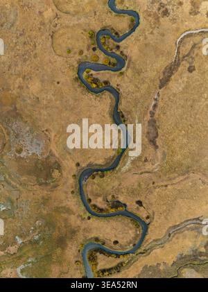 Vue aérienne d'un ruisseau sinueux coulant à travers des prairies dorées et des arbres de couleur automnale à Sparks Lake dans le comté de Deschutes, Oregon, États-Unis. Banque D'Images