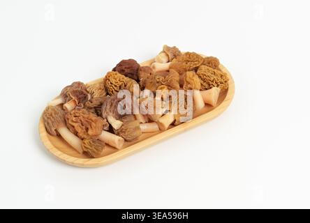 Champignons morilles frais (Morchella esculenta) dans un plat ovale en bambou sur fond blanc Banque D'Images