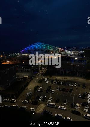 Sotchi, Russie- mai 31 2021 : paysage urbain de nuit avec stade moderne éclairé et parking avec voitures et personnes Banque D'Images