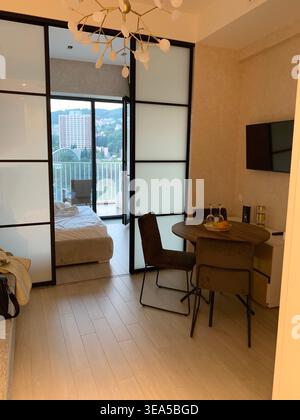 Intérieur moderne et confortable de l'appartement avec coin repas, chambre et vue sur le balcon, design minimaliste avec éclairage chaleureux Banque D'Images