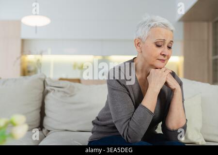 Triste fatigué malade seul déçu femme âgée assise à la maison seule. Une grand-mère malheureuse et mature qui connaît un chagrin relatif mort mauvaise nouvelle. Femme aînée stressée souffrant de solitude Banque D'Images