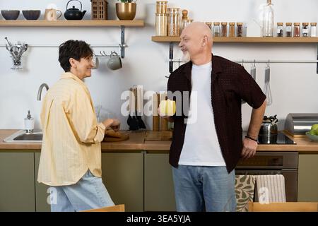 Un couple aîné aimant partage des moments joyeux cuisinant ensemble dans leur cuisine lumineuse. Banque D'Images