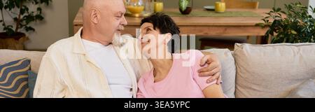 Un couple aîné aimant profite d'un moment tendre ensemble dans leur espace accueillant à la maison. Banque D'Images