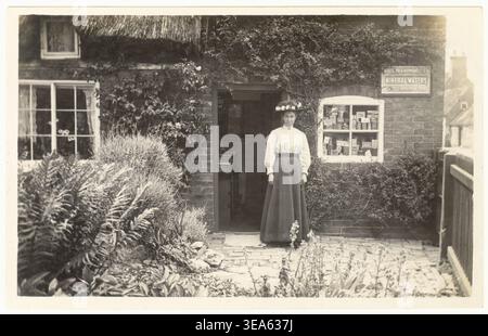 Femme commerçante des années 1900, commerçante indépendante, devant sa boutique de village rural, chez elle, peut-être Newark on Trent, Nottinghamshire, Royaume-Uni Vers 1905 années 1900 Banque D'Images