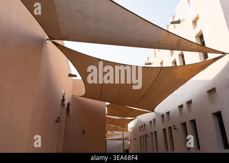 Katara Cultural Village, Doha, Qatar - 23 décembre 2025 : une large perspective de voiles d'ombrage architecturales tendues sur une rue étroite Banque D'Images