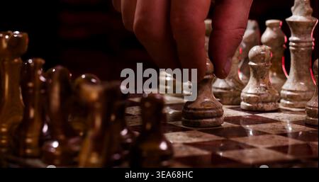 Jeu d'échecs en cours avec joueur déplaçant un pion pendant les heures du soir dans un cadre confortable Banque D'Images