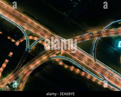 Infrastructure moderne illuminée d'autoroute et de pont la nuit affichant des sentiers légers provenant de la circulation urbaine Banque D'Images